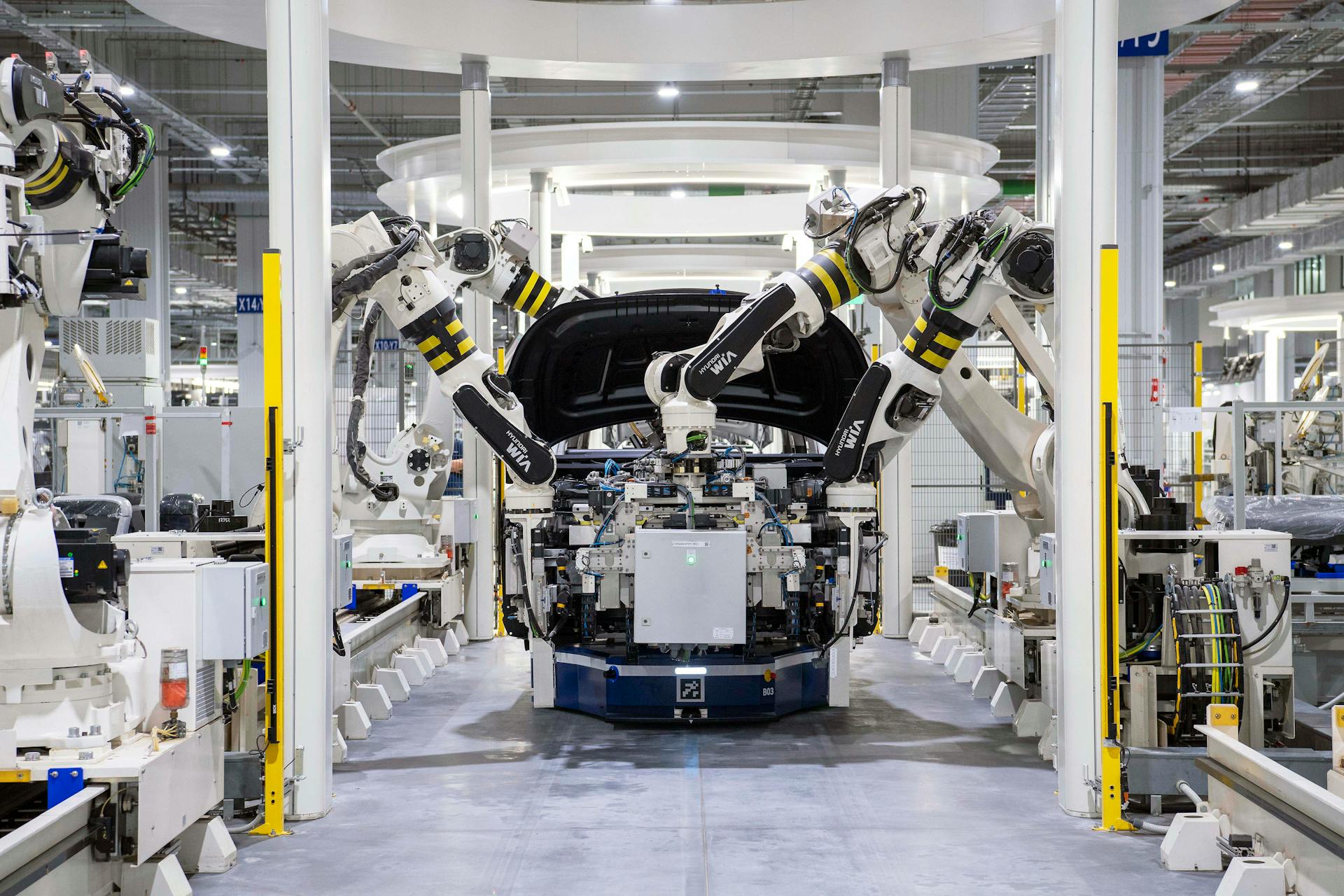 Robotic arms assembling a car on an automated automotive manufacturing production line inside a modern factory